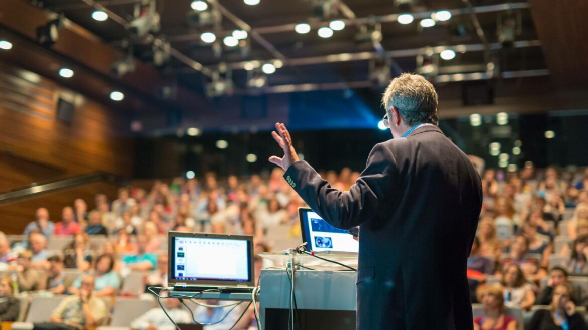 speaker at the hybrid event venue in front of in person audience